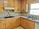 Close up of kitchen details including wood cabinets, a cooktop, and a double basin sink at 1622 N Carolina 98 Hwy W, Louisburg, NC 27549
