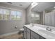 Sunlit bathroom features a double sink vanity, a large mirror, and bright light, complemented by neutral walls and tiled floors at 2007 Watson Rd, Durham, NC 27704
