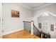 Upper landing with hardwood floors and decorative railing, filled with natural light from the window at 214 Lions Gate Dr, Cary, NC 27518