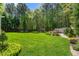 Lush backyard with a large lawn, mature trees, white pergola, and lush landscaping creating a private oasis at 255 Williamston Ridge Dr, Youngsville, NC 27596