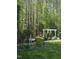 Scenic backyard featuring a white pergola, lush greenery, and mature trees, creating a serene outdoor space at 255 Williamston Ridge Dr, Youngsville, NC 27596