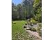Lush backyard with mature trees, blooming flowers, and a stone crane statue adding charm and elegance to the outdoor space at 255 Williamston Ridge Dr, Youngsville, NC 27596