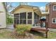 Cozy screened porch with wooden deck, grill, and adjacent brick home and lush greenery at 3011 Kenan Rd, Durham, NC 27704