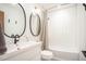 Modern bathroom with a white vanity, matte black faucet, dual mirrors and tub with white subway tile at 3016 Sylvania Dr, Raleigh, NC 27607