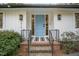 Inviting front entrance with a light blue door, brick steps, black railings, and stylish outdoor lighting fixtures at 3016 Sylvania Dr, Raleigh, NC 27607