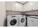 Functional laundry room features Whirlpool appliances, white cabinets, a dark countertop, and patterned floors at 382 Belmont Stakes Ln, Wendell, NC 27591