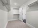 A walk-in closet, carpeted, with white walls and shelving, leading to another carpeted room at 382 Belmont Stakes Ln, Wendell, NC 27591