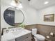 Stylish powder room featuring wainscoting, a round mirror, modern fixtures, and wood look floors at 511 Circle Dr, Burlington, NC 27215