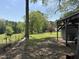 View of the grassy backyard featuring outbuildings and mature trees at 5138 Nc 56, Franklinton, NC 27525