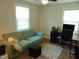 Comfortable living room with a green couch, desk with monitor, and neutral-toned walls at 5531 Autry Rd, Rocky Mount, NC 27803