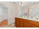 Well-lit bathroom with dual sinks, wooden cabinets, and a large mirror at 8721 Owl Roost Pl, Raleigh, NC 27617