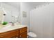 Bright bathroom featuring a wood vanity with sink, a large mirror, and shower with white curtain at 8721 Owl Roost Pl, Raleigh, NC 27617