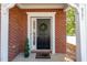Inviting front entrance with brick surround, a classic black door with a wreath, and manicured greenery at 8721 Owl Roost Pl, Raleigh, NC 27617