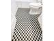 Close-up of the black and white checkerboard bathroom floor and toilet at 919 E Main St, Haw River, NC 27258