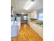 Bright kitchen with white appliances, cabinetry, laminate countertops, and wood-look vinyl flooring at 919 E Main St, Haw River, NC 27258
