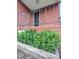 Exterior view showcasing a brick home's side porch and foundation plants at 919 E Main St, Haw River, NC 27258