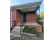 Brick home featuring an open porch, black railing, and manicured shrubbery at 919 E Main St, Haw River, NC 27258