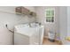 Bright laundry room featuring a window, washer, dryer, storage shelves, and stylish decor at 9904 Erinsbrook Dr, Raleigh, NC 27617
