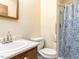 Modest bathroom with a single sink, toilet, and walk-in shower with blue patterned curtain at 103 Wesker Cir, Durham, NC 27703