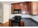 Well-lit kitchen featuring black appliances, including microwave and range, and rich wood cabinetry at 104 Mainline Sta, Morrisville, NC 27560