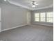 Large primary bedroom featuring tray ceiling, ceiling fan, plush carpeting, and three windows at 104 Mainline Sta, Morrisville, NC 27560