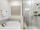 Bright bathroom features a soaking tub, and glass enclosed shower with gray tiled surround at 1116 Ciandra Barn Way, Apex, NC 27523