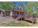 Home featuring a stone exterior, covered entryway, and spacious deck with a pergola, surrounded by green trees at 11209 Sedgefield Dr, Raleigh, NC 27613