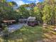 A beautifully landscaped two-story home featuring a stone facade, wooden deck, gazebo, and convenient carport at 11209 Sedgefield Dr, Raleigh, NC 27613