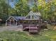 Two-story home featuring stone accents, a wooden deck, and unique architectural details amidst a green lawn at 11209 Sedgefield Dr, Raleigh, NC 27613
