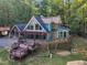 Two-story home with a stone chimney and pergola-covered deck, complemented by lush greenery and a well-maintained lawn at 11209 Sedgefield Dr, Raleigh, NC 27613
