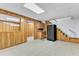 Basement kitchenette with wood paneling, cabinets, and stairs to the upper floor at 11209 Sedgefield Dr, Raleigh, NC 27613