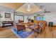 Expansive living room with a tray ceiling, chandelier, grand piano, and comfortable leather furniture at 11209 Sedgefield Dr, Raleigh, NC 27613