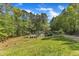 View of the private tennis court surrounded by lush lawn and mature trees, ideal for recreation at 11209 Sedgefield Dr, Raleigh, NC 27613