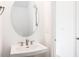 Bathroom featuring a sleek pedestal sink, round mirror, and modern fixtures at 113 Sepals Pl, Wendell, NC 27591