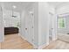Hallway with light LVP flooring, white doors, and views into the living room with fan and fireplace at 115 Buckskin Dr, Louisburg, NC 27549