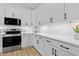 Modern white kitchen with stainless appliances, stone countertops, subway tile backsplash, and luxury vinyl plank flooring at 115 Buckskin Dr, Louisburg, NC 27549