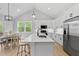Modern kitchen boasts white cabinets, stainless appliances, island with seating, and open dining area at 115 Buckskin Dr, Louisburg, NC 27549