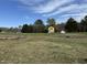 Exterior shot of a property with additional buildings and a sprawling grassy lot surrounded by trees at 1278 Valley Ct, Zebulon, NC 27597