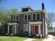 Charming gray duplex with red doors, white trim, and a small front lawn under a clear, blue sky at 1308 Wake Forest Rd, Raleigh, NC 27604