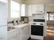 Traditional kitchen with white cabinets, stainless steel appliances, and a window above the sink at 1308 Wake Forest Rd, Raleigh, NC 27604
