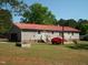 View of backyard with a red roof house, patio, lush greenery, and trees, creating a peaceful outdoor space at 136 Scramble Rd, Erwin, NC 28339