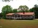 Spacious home with a red metal roof, attached carport, and lush landscaping, perfect for comfortable living at 136 Scramble Rd, Erwin, NC 28339