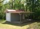 External view of a gray shed with a covered parking or storage area and adjacent trees at 136 Scramble Rd, Erwin, NC 28339