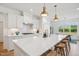 Bright kitchen boasts white cabinets, a spacious island with seating, and modern pendant lighting at 143 Sallyport Ct, Raleigh, NC 27603