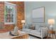 Stylish living room with exposed brick accent wall and neutral colored furnishings at 1535 Caraleigh Mills Ct # 104, Raleigh, NC 27603