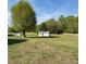 Expansive backyard with lush greenery and multiple storage sheds, perfect for outdoor activities and storage at 1829 Stewart Farm Rd, Henderson, NC 27537