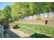 Landscaped backyard features a stone retaining wall, lush green lawn, and a charming patio area for outdoor enjoyment at 212 Mickleson Ridge Dr, Raleigh, NC 27603