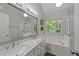 Elegant bathroom featuring double sinks, a large soaking tub, a walk-in shower, and a window with wooded views at 2520 Ashley Ct, Raleigh, NC 27607