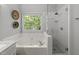 Bright bathroom featuring a tub, walk-in shower, and a window with a view of lush greenery at 2520 Ashley Ct, Raleigh, NC 27607