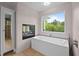 Spa-like bathroom with a modern tub, a large window, and a fireplace at 255 Seven Island Rd, Pittsboro, NC 27312